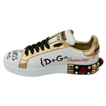 Designer white sneaker with gold metallic accents, graffiti text, black laces, and studded rose details