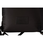 Close-up of black designer backpack with leather patch and adjustable straps