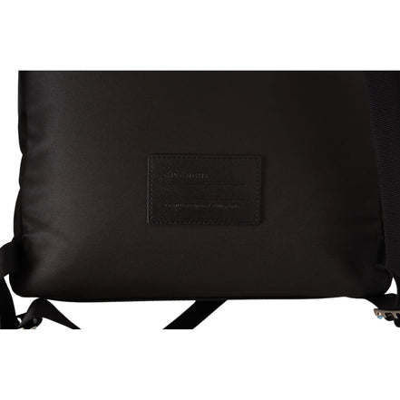 Close-up of black designer backpack with leather patch and adjustable straps