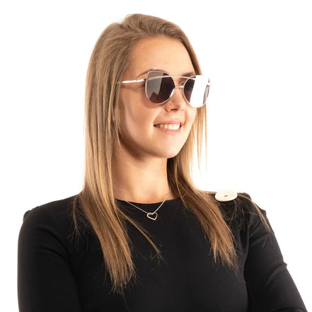 Woman wearing mirrored aviator sunglasses, black top, and heart necklace against white background