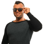 Man wearing black sunglasses and a dark textured sweater, posing confidently against white background